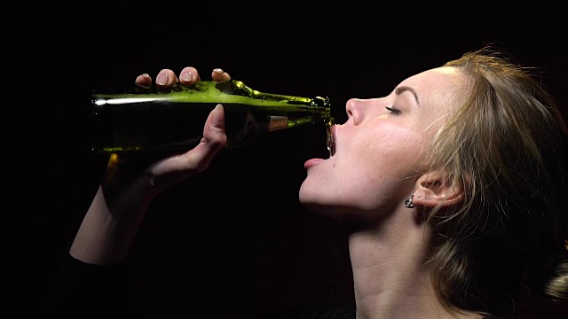 金发女郎从一个玻璃瓶里喝啤酒，慢镜头视频下载
