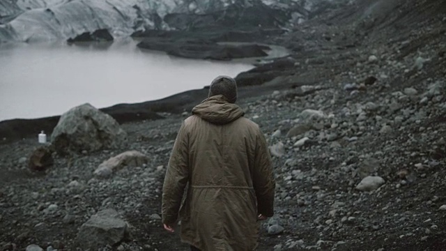 年轻男子独自走在冰湖上的背影。在冰岛冰川附近的火山中徒步旅行的男性视频素材