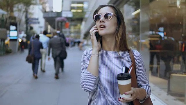 年轻美丽的女商人戴着太阳镜在市中心打电话和喝咖啡的肖像视频素材