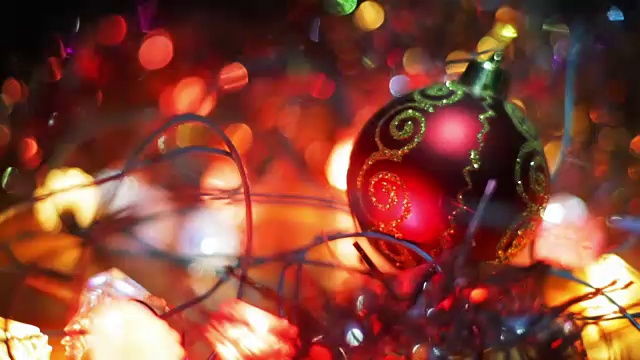 圣诞节和新年装饰。把小玩意挂起来。抽象模糊散景假日背景。一个红色的圣诞树玩具球放在木制的表面上，周围环绕着花环视频素材