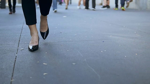 年轻女性在市中心行走的特写镜头。穿着黑色高跟鞋的女商人。慢动作视频素材