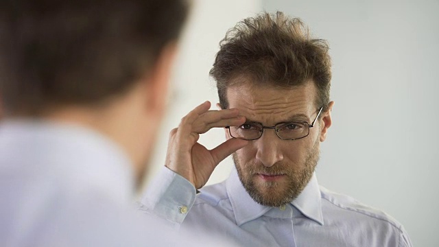 男人不满意他的眼镜和考虑视力矫正程序视频素材