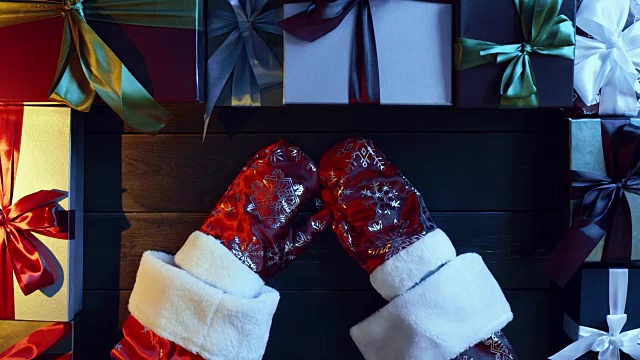 穿圣诞老人装的人戴上手套放在木制装饰的新年桌子上，从上往下射视频下载