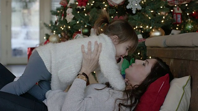 迷人的单身母亲和她的小女儿在圣诞树前玩耍视频素材
