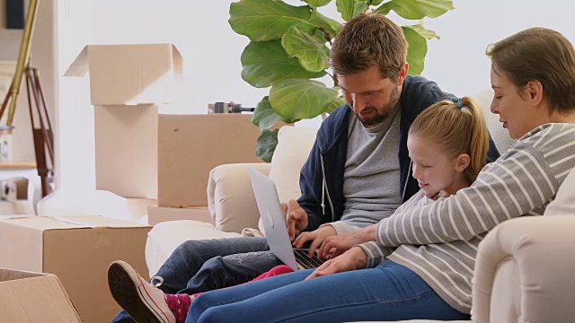 一家人坐在沙发上，用笔记本电脑在他们的新家4K 4K视频素材