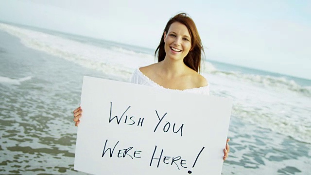 微笑的年轻白人女性拿着白色的留言板视频素材