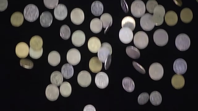 闪亮的金属硬币落在黑色的背景上视频素材