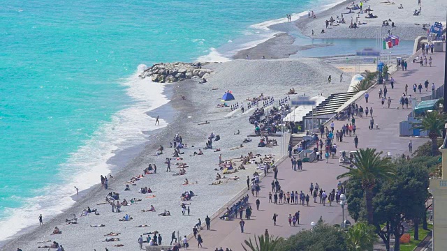 在尼斯度假城市，人们日光浴和行走在堤岸上视频素材