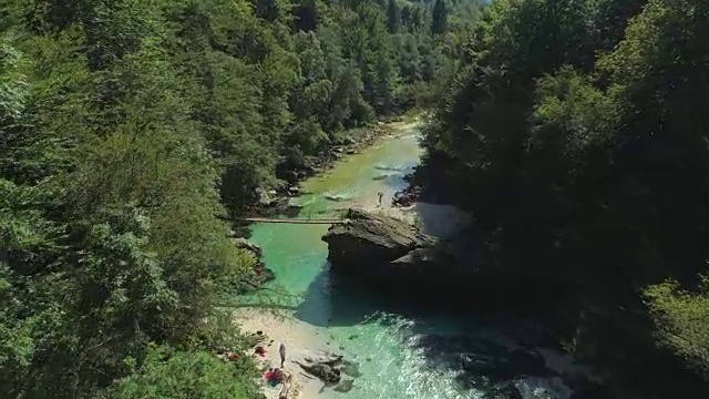 AERIAL:游客们在森林山谷的河岸上享受他们的暑假视频素材