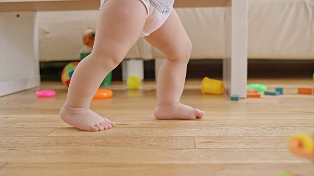 SLO MO一个赤脚婴儿的腿在客厅里行走视频下载