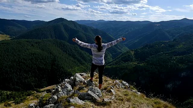 女人举起手臂在山顶看日落的观点徒步女孩举起手臂庆祝生活风景自然景观享受假期旅行冒险视频素材