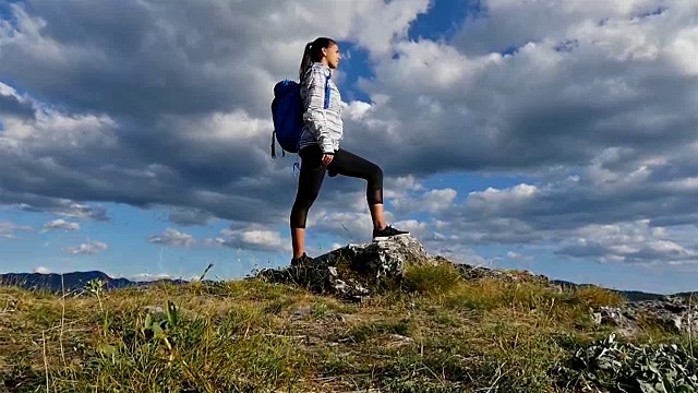 女人背着背包在山顶看日落，徒步女孩庆祝生活，风景优美的自然景观，享受假期旅行冒险视频素材