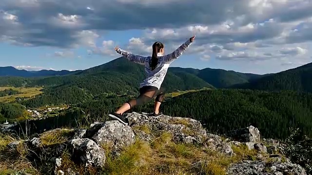 低角度的女人在山顶延伸在日落的观点远足女孩庆祝生活风景自然景观享受假期旅行冒险视频素材