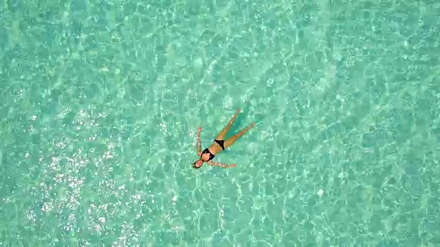一个女人在热带岛屿上漂浮和游泳的无人机视图。视频素材