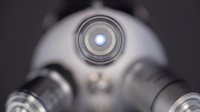 一只手转动着一块显微镜镜头，其中一个会发光视频素材