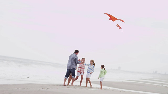 健康的白人家庭玩玩具风筝落海滩视频素材