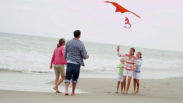 年轻的白人女孩父母玩沙滩玩具风筝视频素材