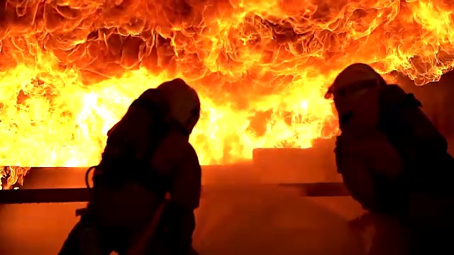 强壮和勇敢的消防员在燃烧的大楼值班。消防过程中，两名消防员正在用软管和水灭火。视频素材