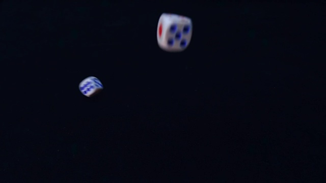 两个白色的骰子旋转着落下，在慢动作中跳跃到黑色的表面视频素材