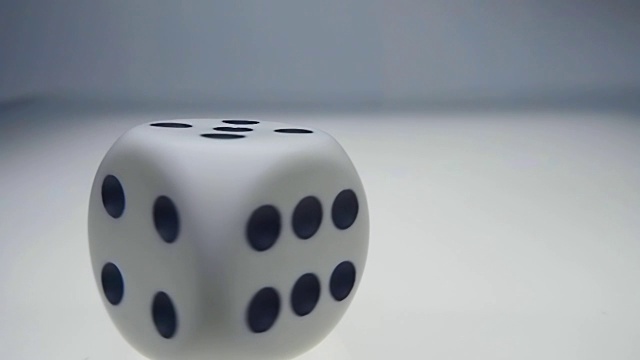 白色的骰子旋转着落下，从白色光滑的发光表面上跳下来视频素材