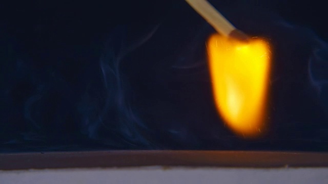 手里的火柴在火柴盒的一侧移动，点燃了火焰视频素材