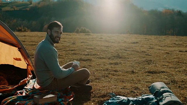 一个人坐在山上，喝着咖啡野营视频素材