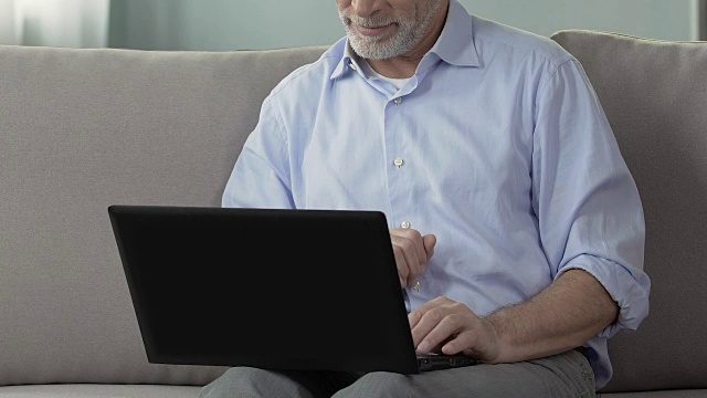 老人坐在沙发上，用笔记本电脑，在家工作，工程项目视频素材
