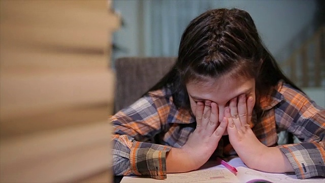 疲惫的女学生在书桌上堆着一堆书学习视频下载