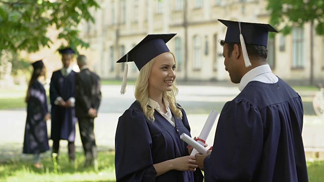 男、女毕业生毕业典礼后谈话，大学教育，成年生活视频素材