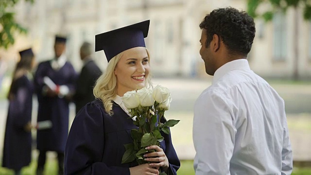 男朋友送花给他毕业的女朋友，拥抱特别的场合视频素材