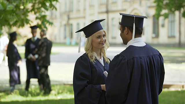 研究生们穿着学术服装拥抱和纺纱，大学友谊视频素材