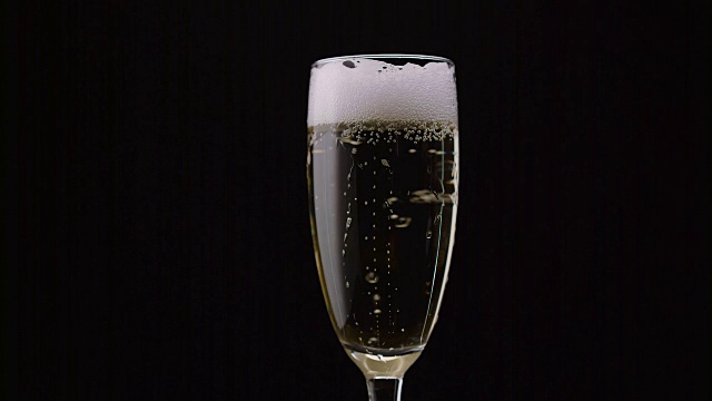 一杯里面有旋转气泡的香槟。黑色背景。近距离视频下载