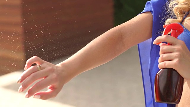 一个女孩的特写，喷在你的手上防晒油。视频素材