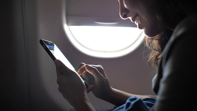 女性在飞机上使用智能手机视频下载