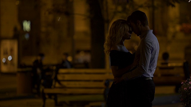 浪漫的情侣在晚上的城市公园里拥抱并享受约会，爱视频素材