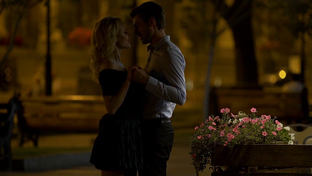 男性牵着女友的手，拥抱她，晚上在城市公园约会，爱视频素材