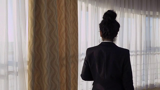 一位女商人走到酒店房间的窗户附近视频素材