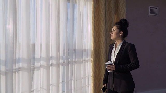 时尚的女商人看着酒店房间的窗户视频素材