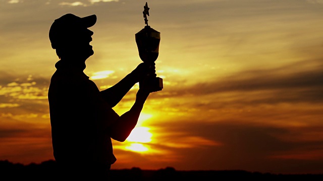 日落剪影成功的男性高尔夫球员持有获奖奖杯视频素材