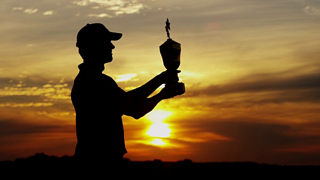 日落剪影的高尔夫锦标赛冠军持有奖杯视频素材