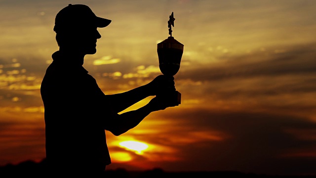 日落剪影赢得职业男性高尔夫球与奖杯视频素材