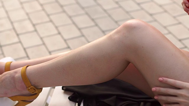 女人在晒黑之前在腿上喷防晒霜。视频素材