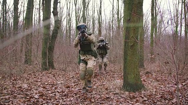 一群年轻的武装士兵在一个地区的武装冲突中穿着制服以突击步枪瞄准森林，慢镜头，软式视频下载