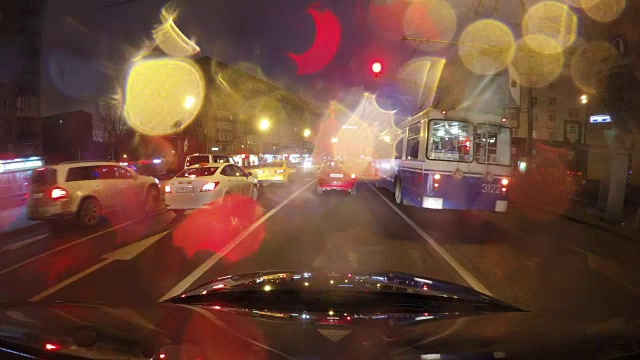 快速城市行驶夜间道路POV时间推移的挡风玻璃和车罩，雨夜，雨滴在玻璃上视频素材