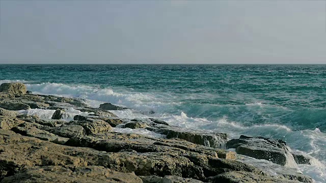 慢动作:巨大的海浪溅在岩石海岸的景象。视频下载