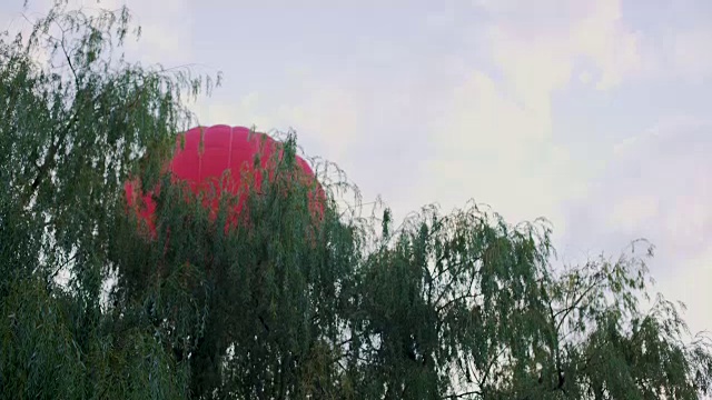 红色热气球飞过树林，休闲活动，极限运动视频素材