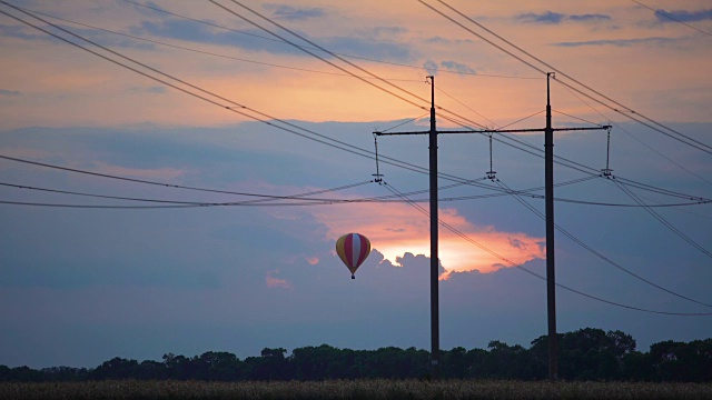 巨大的热气球在日落时飞过田野，梦幻般的景象视频素材