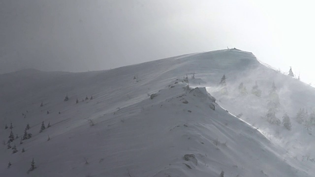 在冬季的暴风雪中，高速风从山脊上吹起雪花视频素材
