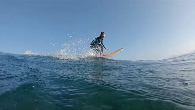 慢动作，近:冲浪者摇他的头，而骑在岩石海岸附近的波浪视频素材