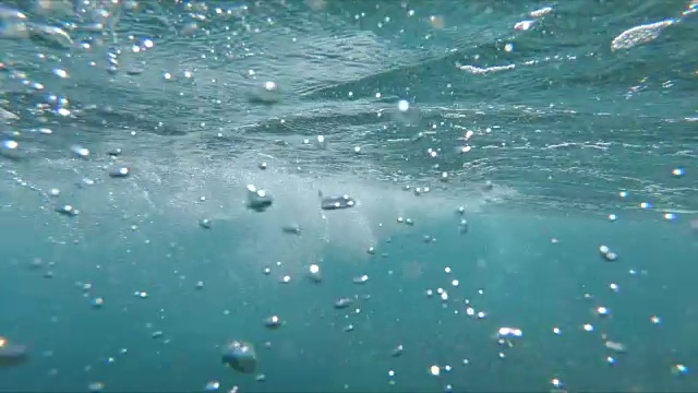 慢镜头特写:职业男性冲浪者骑在蓝色的破浪在一个阳光明媚的日子。视频素材